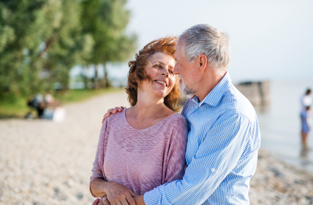 A senior couple on a holiday on a walk by the lake.